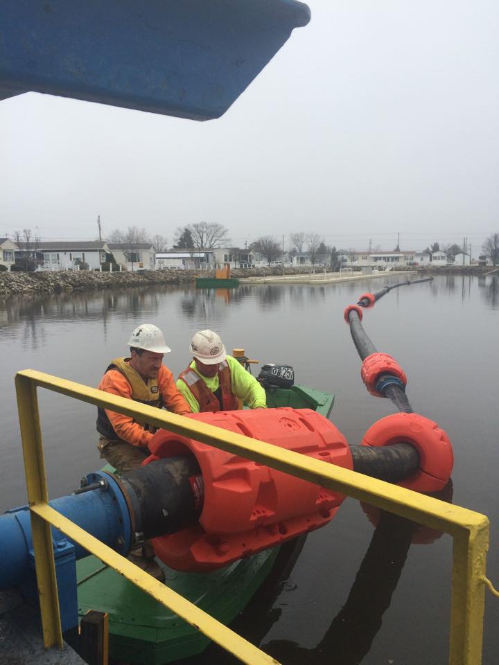 Men installing Pipe Floats (dredge floats or float collars) on pipe over water